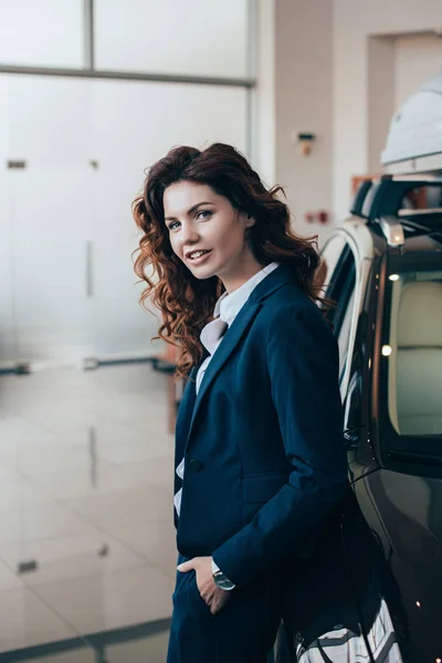 Smiling businesswoman standing near car and looking at camera — Stock Photo