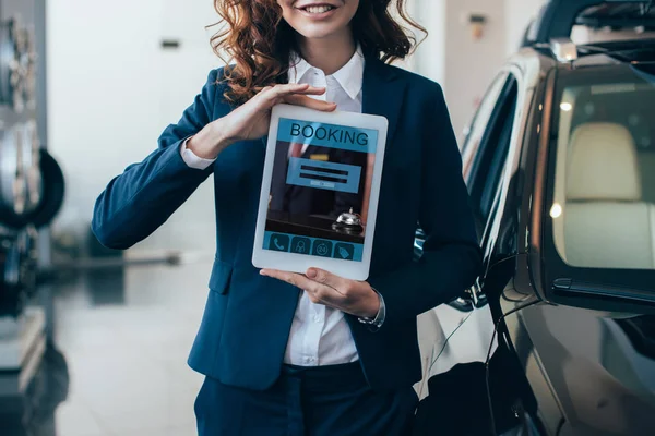 Обрізаний вид бізнес-леді, що тримає цифровий планшет з додатком бронювання на екрані — стокове фото
