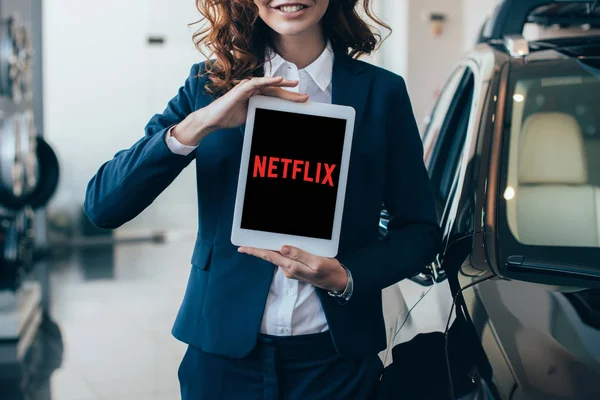 Partial view of businesswoman holding digital tablet with netflix app on screen — Stock Photo