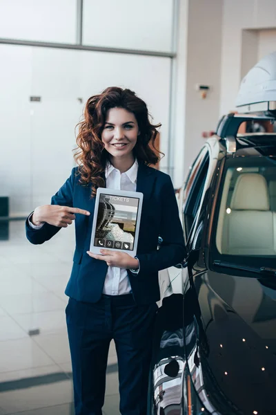 Enfoque selectivo de la mujer de negocios que sostiene el teléfono inteligente con la aplicación de boletos en la pantalla y la mano en el bolsillo - foto de stock