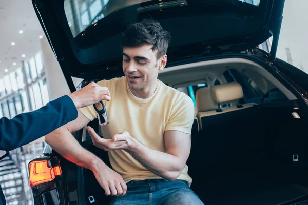 Vue partielle du concessionnaire de voiture donnant des clés de voiture à homme beau heureux — Photo de stock