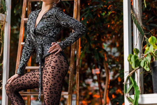 Vista ritagliata di donna sexy in collant nero in piedi vicino a scala di legno in aranciata — Foto stock