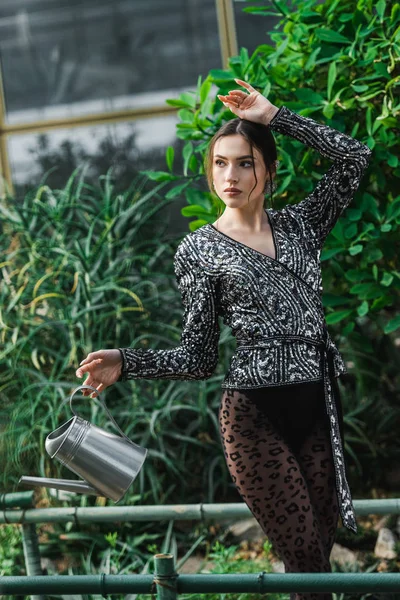 Sexy young woman in pantyhose holding watering can in orangery — Stock Photo