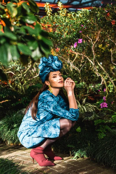 Elegante jovem mulher de vestido azul e turbante sentado em orangery — Fotografia de Stock