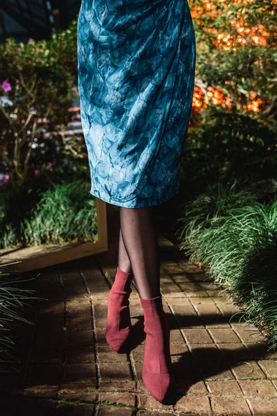 Vista recortada de la mujer joven en vestido azul y zapatos marrones en naranja - foto de stock