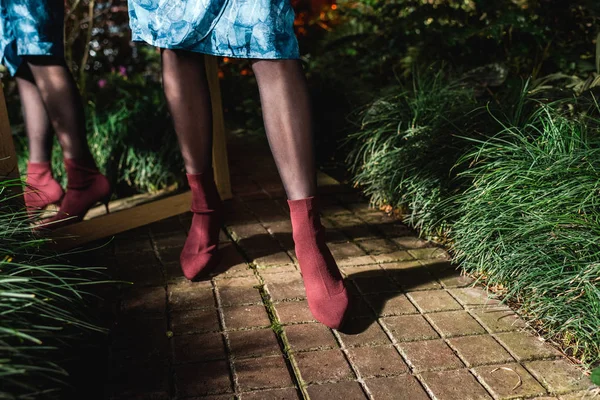 Cropped view of young woman in blue dress and brown shoes in orangery — Stock Photo