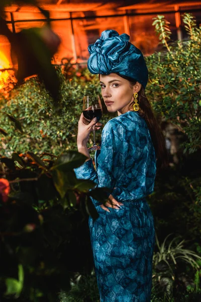 Attraktive Frau im blauen Turban mit einem Glas Rotwein in der Orangerie — Stockfoto