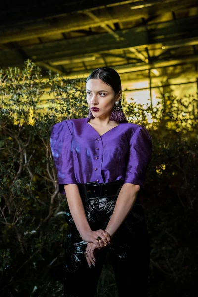 Nachdenkliche junge Frau in lila Bluse schaut in Orangerie weg — Stockfoto