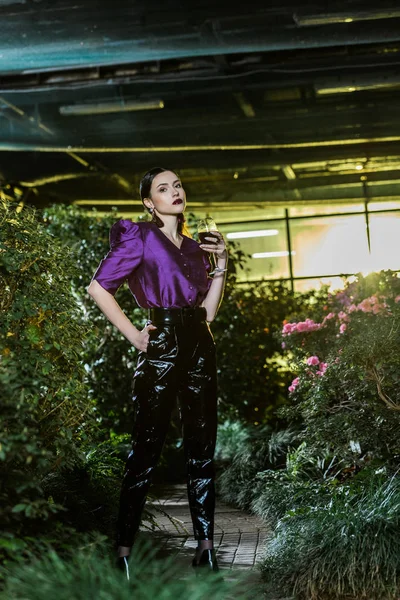 Atemberaubende junge Frau in lila Bluse mit Weinglas in der Orangerie — Stockfoto