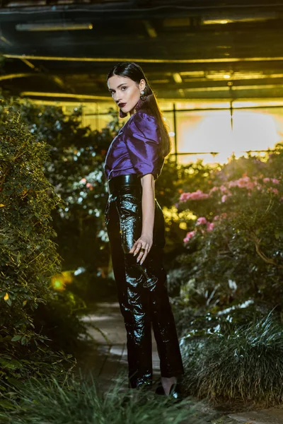 Ganzkörperansicht der attraktiven Frau in Lederhosen mit Weinglas in der Orangerie — Stockfoto