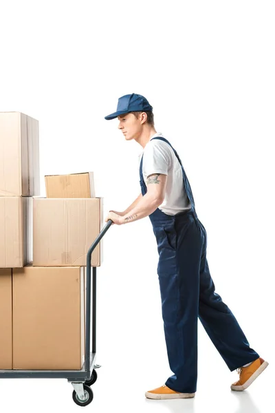 Mover in uniform transporting cardboard boxes on hand truck isolated on white — Stock Photo