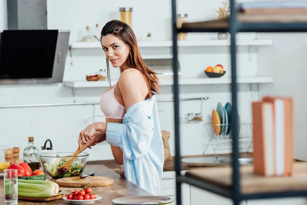Сексуальная девушка в нижнем белье и рубашке, готовящая овощной салат — стоковое фото