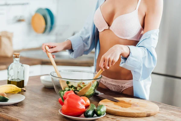 Vista cortada de menina sexy em roupa interior e camisa cozinhar salada de legumes — Fotografia de Stock