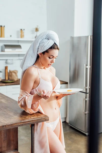 Surprised sexy girl in underwear with towel on head holding plate with fried egg — Stock Photo