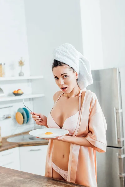 Sexy girl in underwear with towel on head holding plate with fried egg — Stock Photo