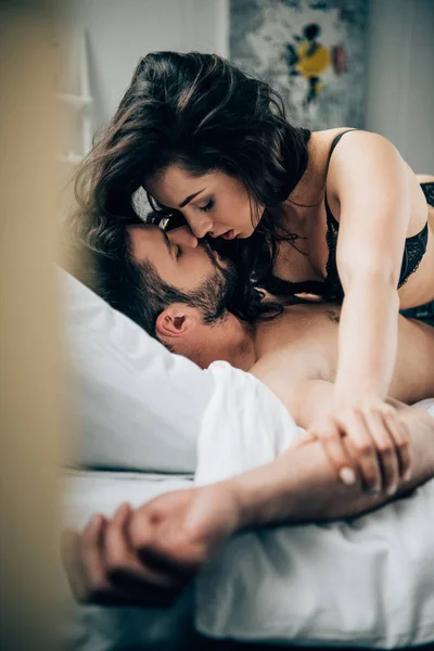 Selective focus of passionate man and woman kissing while lying on bed — Stock Photo