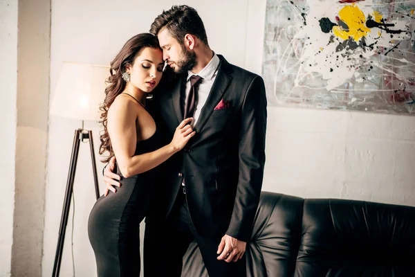 Homme en costume debout avec une femme attrayante en robe noire — Photo de stock