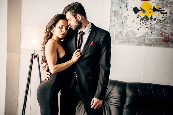 Man in suit standing with attractive woman in black dress — Stock Photo