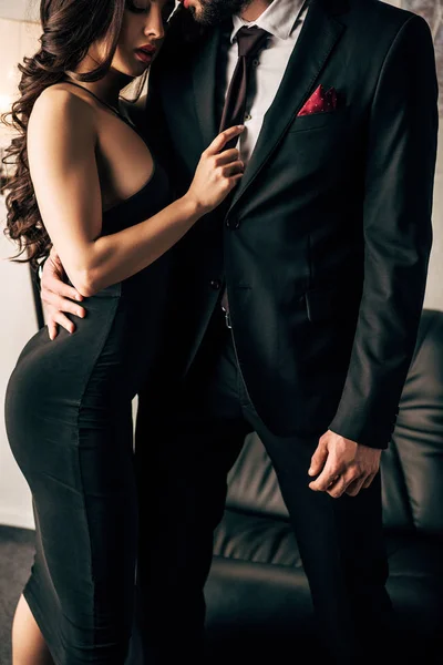 Vista cortada do homem de terno em pé com mulher atraente em vestido preto — Fotografia de Stock
