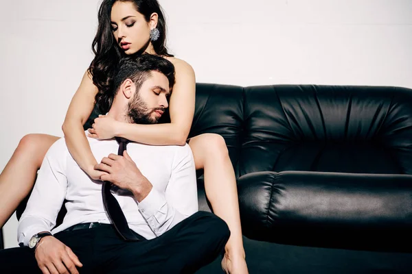 Schöne Frau sitzt auf Sofa und umarmt schönen Freund — Stockfoto