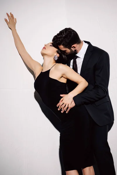 Sexy morena mujer en negro vestido de la mano con el hombre en blanco - foto de stock