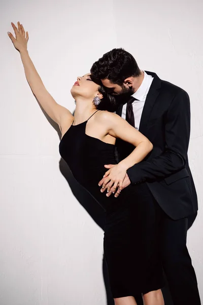 Sexy brunette woman in black dress holding hands with man on white — Stock Photo