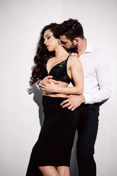 Homem bonito beijando pescoço de mulher bonita em vestido preto no branco — Fotografia de Stock