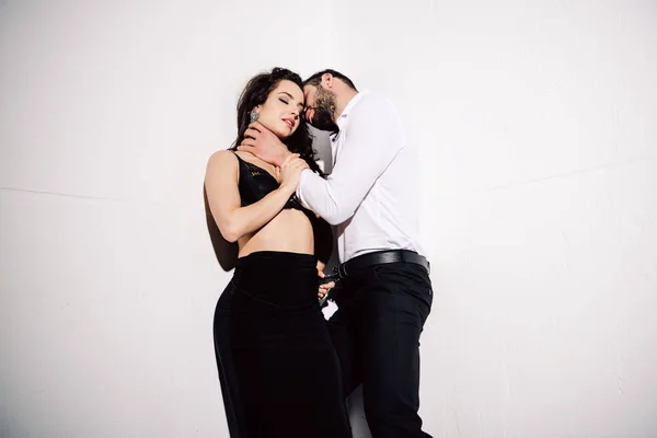 Handsome man touching neck of beautiful woman in black lace bra on white — Stock Photo