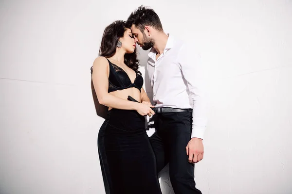 Atractiva mujer en negro sujetador de encaje cinturón de sujeción mientras besa al hombre en blanco - foto de stock