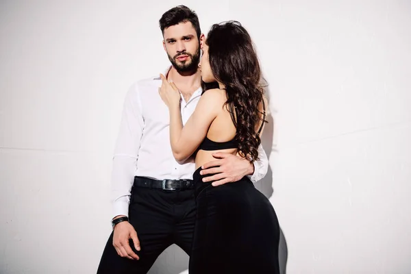 Pretty woman in black bra touching handsome bearded man on white — Stock Photo