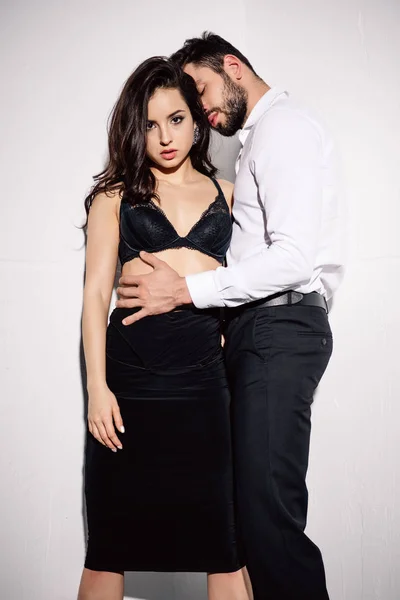 Sexy woman in black bra standing with handsome bearded man on white — Stock Photo