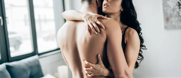 Panoramic shot of sexy woman scratching back of shirtless man in bedroom — Stock Photo