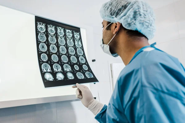 Foyer sélectif du médecin dans la casquette médicale et le gant de latex tenant la radiographie dans la clinique — Photo de stock