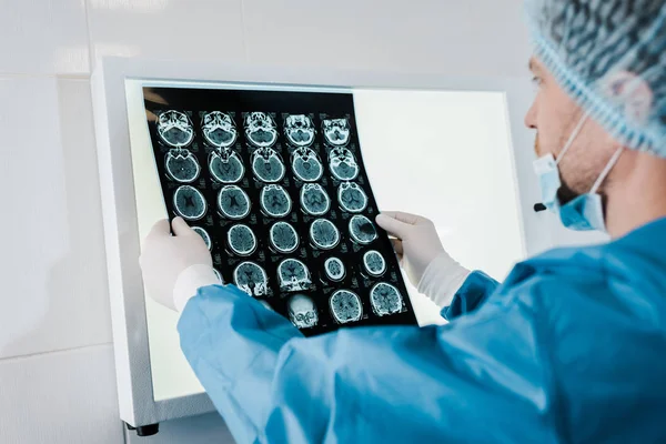 Foyer sélectif du médecin en bonnet médical et gants en latex tenant des rayons X en clinique — Photo de stock
