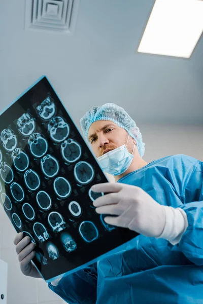 Vista a basso angolo del medico nel cappuccio medico e uniforme tenuta a raggi X in clinica — Foto stock