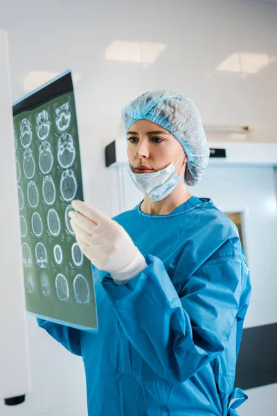 Médico atraente em tampa médica e uniforme segurando raio-x na clínica — Fotografia de Stock