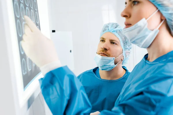 Selective focus of doctors in uniforms looking at x-ray in clinic — Stock Photo