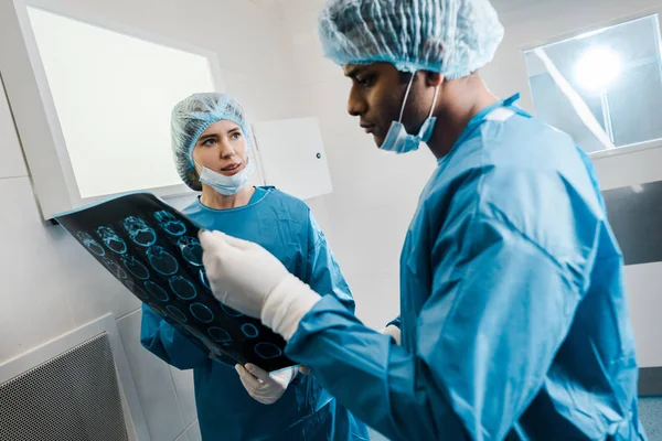 Good-looking and beautiful doctors in uniforms and medical masks talking about x-ray — Stock Photo