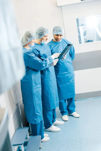 Красиві і красиві лікарі в уніформі і медичні маски говорять про рентгенівський знімок — стокове фото