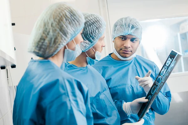 Селективное внимание врачей в униформе и медицинских масках, говорящих о рентгеновском снимке — стоковое фото