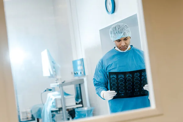Красивий лікар в уніформі та медичній шапці, що тримає рентген в клініці — стокове фото