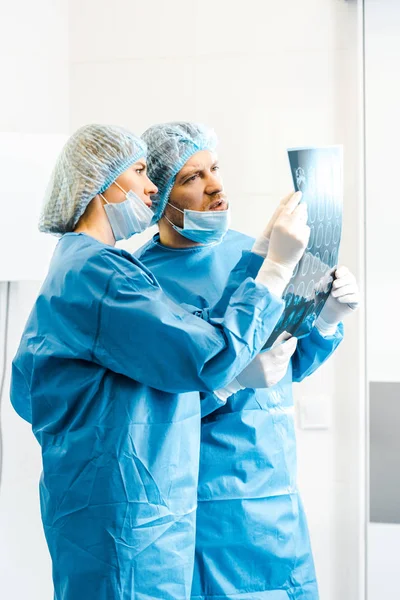 Handsome and attractive doctors in uniforms holding x-ray and talking — Stock Photo