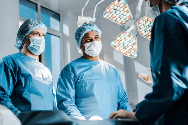 Селективное внимание врачей и медсестры в униформе и медицинских масках говорить — стоковое фото