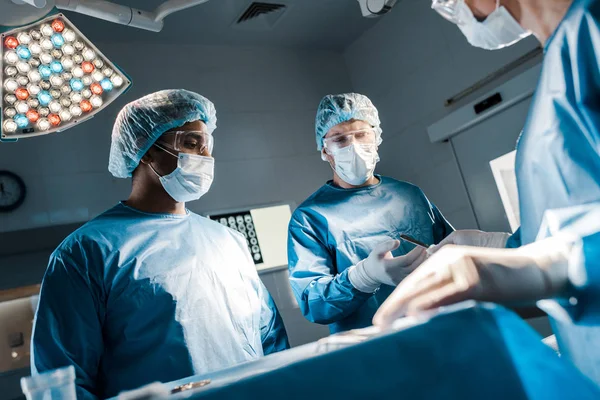 Médicos e enfermeiros de uniformes e máscaras médicas na sala de cirurgia — Fotografia de Stock