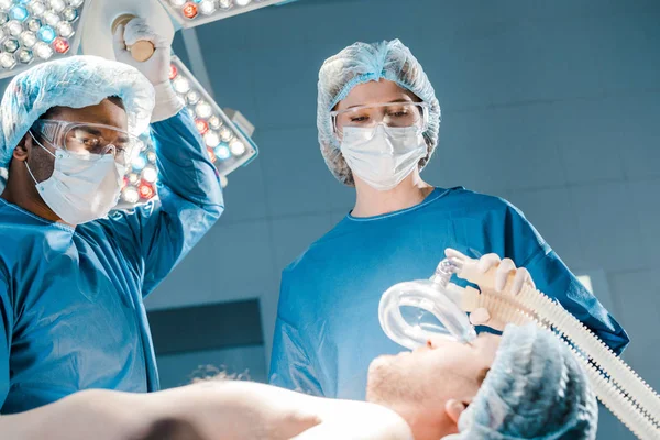 Selective focus of patient, doctor and nurse in uniforms and medical caps holding mask — Stock Photo