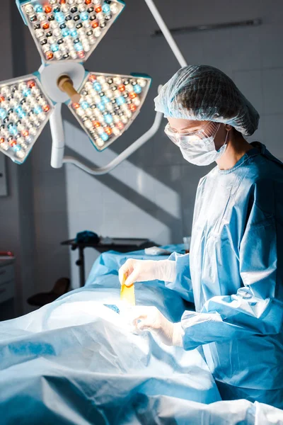 Медсестра в уніформі та медичній шапочці тримає смужку в операційній кімнаті — стокове фото