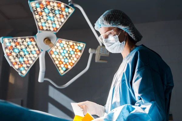 Infirmière en uniforme et bande de maintien de casquette médicale dans la salle d'opération — Photo de stock