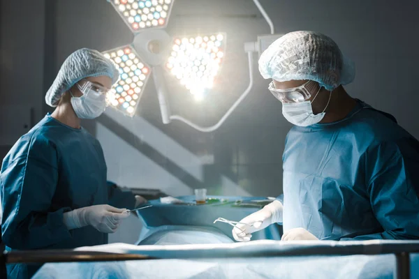 Chirurgien et infirmier en uniforme et casquettes médicales en opération — Photo de stock