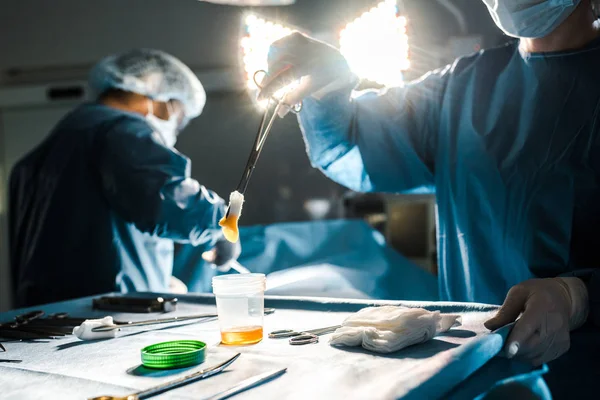 Selective focus of surgeon doing operation and nurse holding tampon in operating room — Stock Photo
