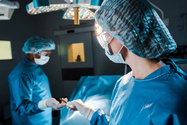 Selektiver Fokus der Krankenschwester, die dem Chirurgen im Operationssaal medizinische Geräte zur Verfügung stellt — Stockfoto